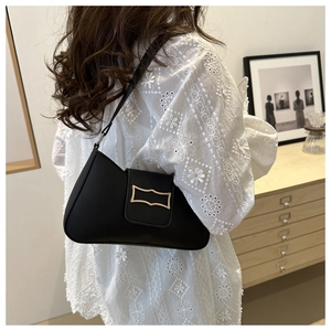 Détail du sac croissant noir avec boucle dorée porté à l'épaule par un mannequin