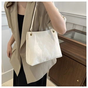 Close-up of white ruched tote bag with embossed fashion lettering and gold metal eyelets