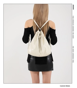 Detail view of cream white PU leather drawstring backpack shown on model back