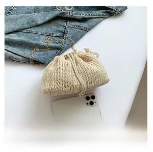 Detail of cream woven bucket bag with drawstring closure and golden chain strap