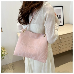 Close-up of light pink tote bag featuring embossed FASHION lettering and gold metal hardware
