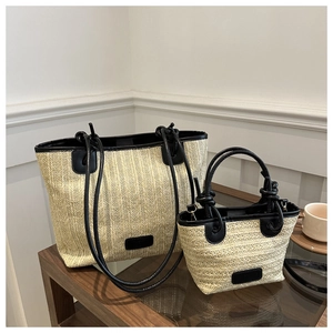 Detail shot of the woven straw texture and premium black leather trim of the tote bag