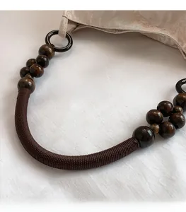 Detail of retro dark brown wood bead and woven rope shoulder strap with metal ring