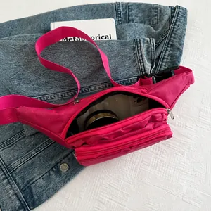 Detalle de riñonera rosa que muestra la capacidad interior con una cámara pequeña