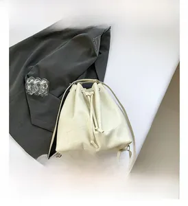 Detail of off-white PU bucket backpack featuring geometric textured patchwork and drawstring