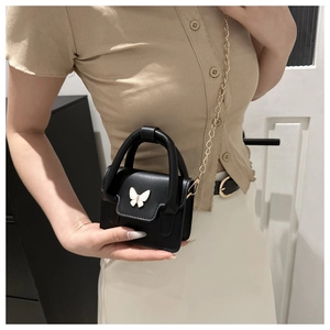 Close-up of black ballet-style mini bag with butterfly clasp and gold chain strap