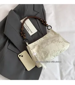 Close-up of floral fabric handbag with wooden bead handle and white tassel detail