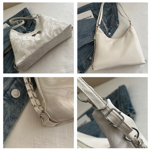 Close-up of marble texture on cream PU leather bag with silver bow hardware and chain