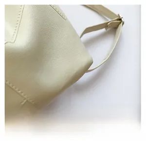 Close-up of cream faux leather tote showing fine lychee grain and silver buckle