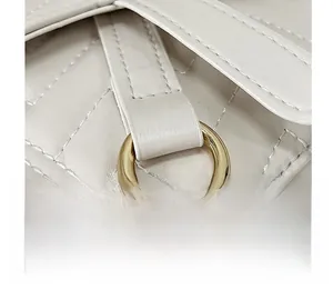 Detailed close-up of quilted beige leather texture and polished gold metal ring hardware