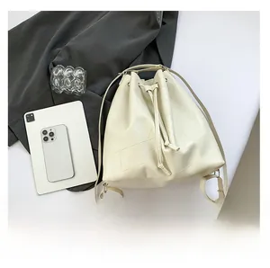 Detail of cream white drawstring bucket bag featuring geometric patchwork embossed texture