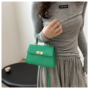 Detail of green crocodile embossed texture bag with metallic gold twist lock and handle