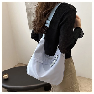 Detail of light purple nylon hobo bag with adjustable strap shown on model shoulder