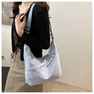Detail of light blue nylon crescent bag with wide shoulder strap and woven zipper pull