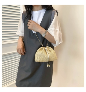 Detail of woven straw bucket bag with gold chain strap and drawstring closure