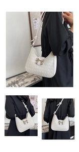 Detailed view of a white woven shoulder bag featuring a silver bow accent and knotted strap