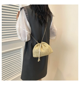 Detail of straw woven bucket bag with drawstring closure and golden chain strap