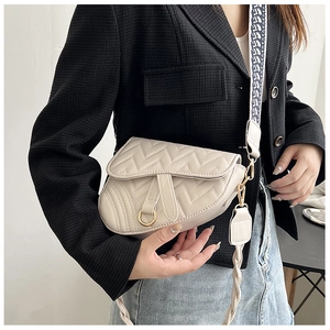 Close-up of ivory quilted saddle bag with V-shaped stitching and golden ring detail