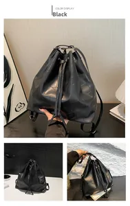 Detail of black geometric patchwork bucket backpack with drawstring closure and matte texture