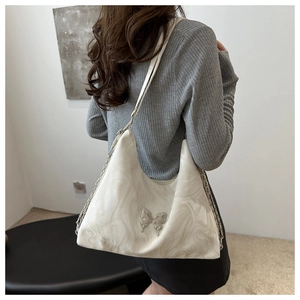 Detail of white marble pattern shoulder bag with silver butterfly buckle and chain strap