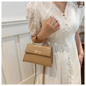 Detail of khaki crocodile-pattern leather handbag with elegant gold twist lock closure