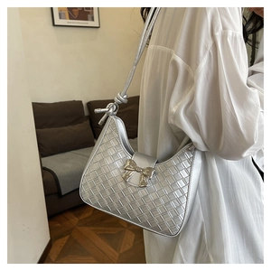 Detail of silver woven shoulder bag featuring a metal bow and knotted strap detail