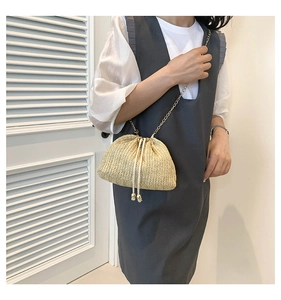 Detail of woven straw bucket bag featuring drawstring closure and gold chain strap