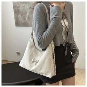 White marble pattern shoulder bag with silver butterfly emblem on grey knit cardigan