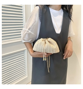 Detail of beige woven drawstring crossbody bag with gold bead accents and metal chain