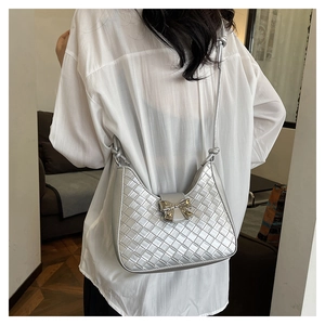 Detail of silver woven hobo bag featuring an elegant metal bow buckle on the shoulder strap