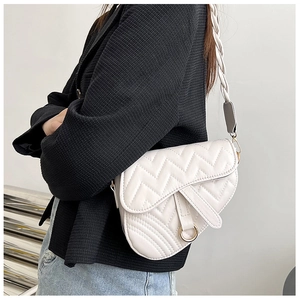 Detail of white saddle bag featuring wavy quilted leather and woven strap detail