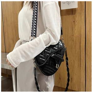 Close-up of quilted black leather saddle bag with embroidered wide strap and gold hardware