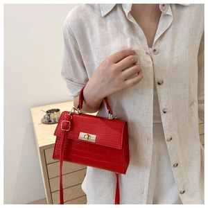 Detail of red crocodile texture handbag with gold metal twist lock and leather strap