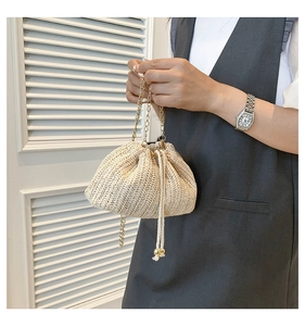 Detail of woven straw texture and gold bead drawstring on chic crossbody bag