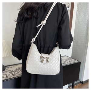 Detail of white woven leather crescent bag with silver bow accent on model