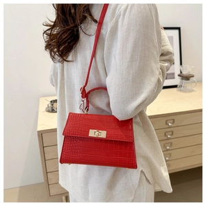 Detail of red crocodile texture handbag with golden buckle and stylish top handle