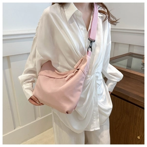 Detail view of light pink pleated tote bag with wide shoulder strap worn by a model