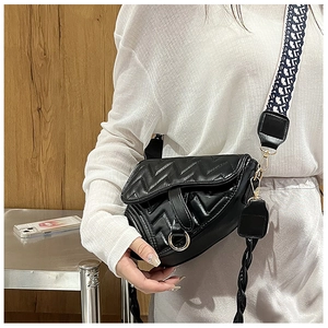 Detail of black saddle bag with V-shaped quilting and decorative golden metal ring