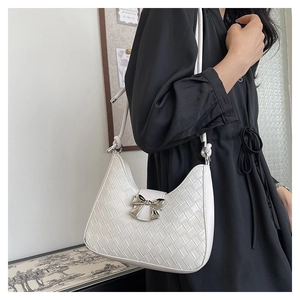 Detail of white woven leather crescent bag with a silver bow clasp worn by a model
