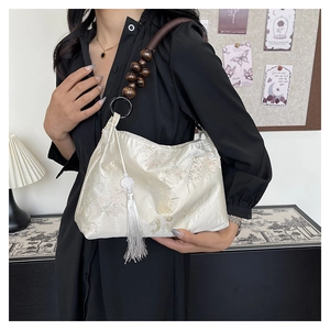 Detail of embroidered satin handbag with wooden bead strap and white silk tassel