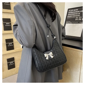 Close-up of black woven shoulder bag featuring a silver metal bow accent and side view
