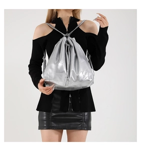 Detail of silver metallic drawstring backpack with geometric patchwork design on model