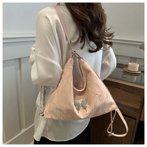 Detail of pink marble pattern hobo bag with silver butterfly charm on a female model