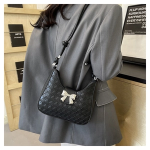 Detail of woven crescent hobo bag in black with silver bow accent and knotted strap