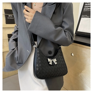 Detailed view of woven crescent shoulder bag with silver bow accent on a female model