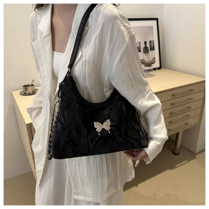 Detail of black marble textured shoulder bag with silver butterfly buckle and chain