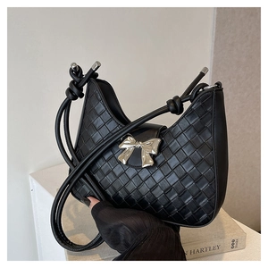 Detail of black woven hobo shoulder bag featuring a silver bow metal decoration