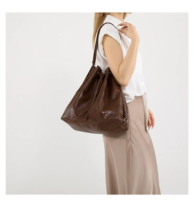 Detail of dark brown PU leather bucket bag with drawstring closure and stitched panels