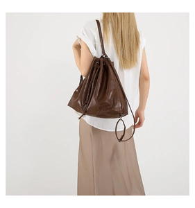 Detail of dark brown leather tote bag with patchwork texture on model's back