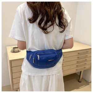Detail of dark blue nylon waist bag with multiple zipper pockets worn by a model